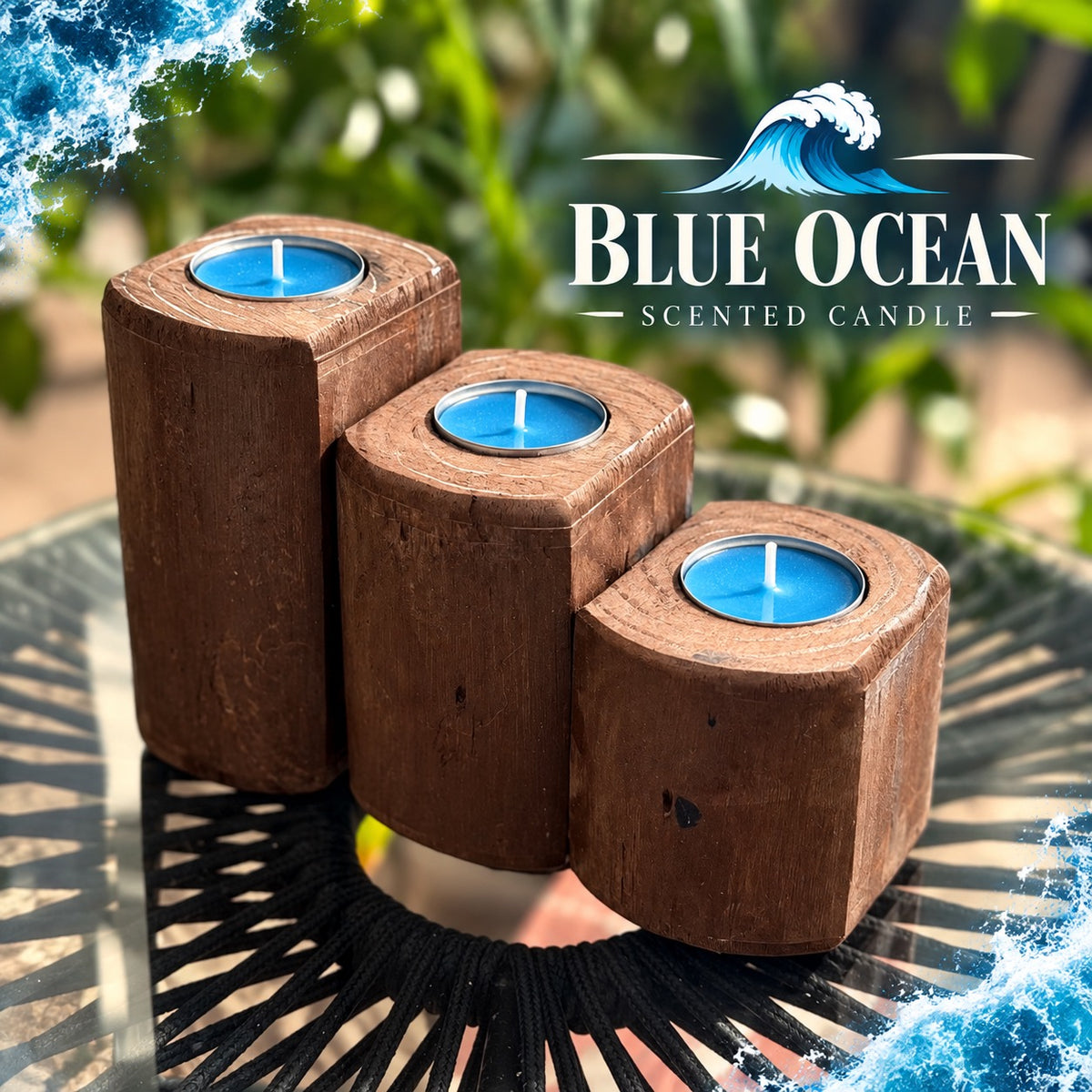 Three-piece American Brown wooden tea light candle holder set with blue tea light candles, arranged in graduated sizes on a black outdoor table, with a tropical garden background and Blue Ocean Scented Candle text.