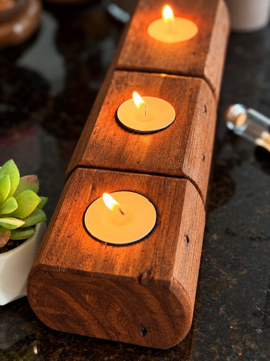 Three-piece American Brown wooden tea light candle holder set arranged in a row, showing the holders from a top-down angle with lit tea light candles.